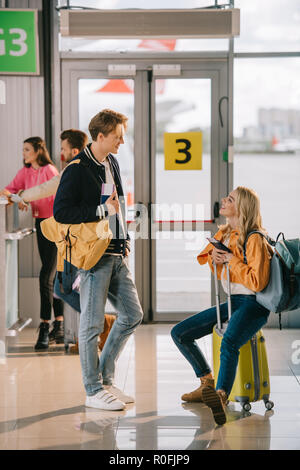young man and woman with passports and luggage talking in airport terminal Stock Photo
