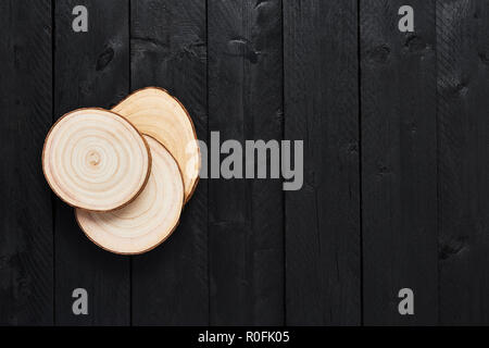 Top view of transverse wooden saw cuts on black wooden table with copy space. Stock Photo