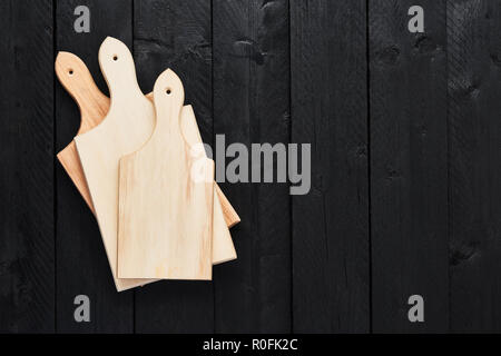 Top view of three stacked chopping boards on black wooden table with copy space. Stock Photo