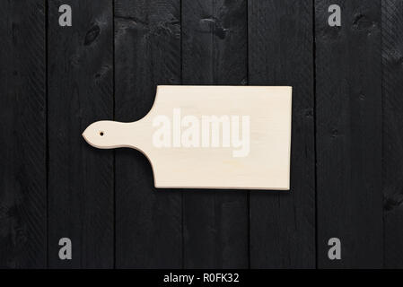 Top view of small empty chopping board on black wooden table with copy space. Stock Photo