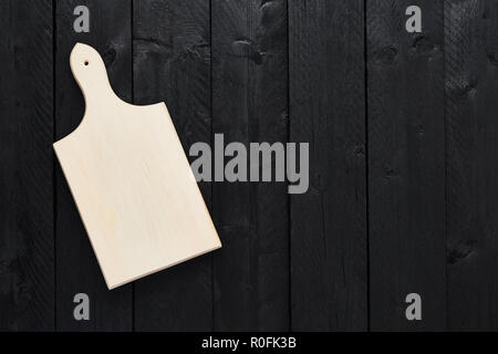 Top view of empty chopping board on black wooden table with copy space. Stock Photo