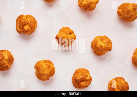 Close up of assorted fresh cream puff cakes on rose background. Top view. Stock Photo
