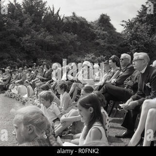 1967, picture shows a large group of spectators watching an event at the Tring Arts summer festival, Tring, Hertfordshire, England, UK. The festival was outdoors at Tring Park, the school for the Performing Arts, the home of the Arts Educational School. Stock Photo