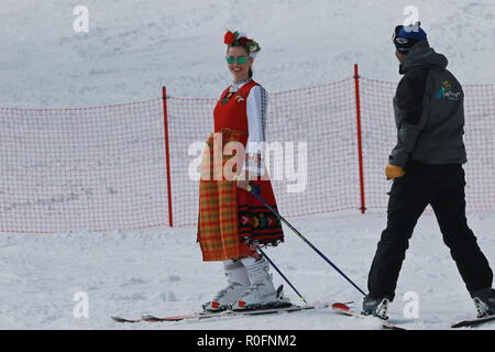 Skiing with Bulgarian flags at Pamporovo ski resort, Bulgaria. People dressed with traditional Bulgarian clothes skiing with the national flag. Stock Photo