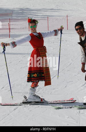 Skiing with Bulgarian flags at Pamporovo ski resort, Bulgaria. People dressed with traditional Bulgarian clothes skiing with the national flag. Stock Photo