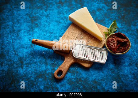 https://l450v.alamy.com/450v/r0fp98/grated-parmesan-cheese-and-metal-classic-grater-placed-on-wooden-cutting-board-r0fp98.jpg
