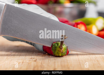 cook cutting hot chili peppers on a wooden board Stock Photo