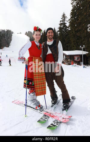 Skiing with Bulgarian flags at Pamporovo ski resort, Bulgaria. People dressed with traditional Bulgarian clothes skiing with the national flag. Stock Photo