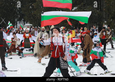 Skiing with Bulgarian flags at Pamporovo ski resort, Bulgaria. People dressed with traditional Bulgarian clothes skiing with the national flag. Stock Photo