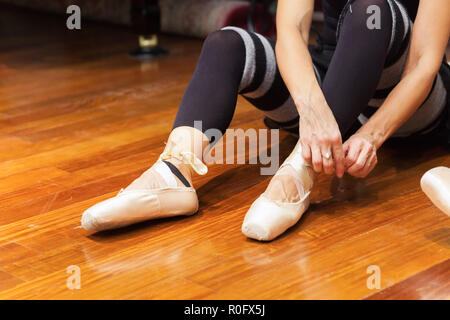 Classical dancer adjusting her shoes Stock Photo