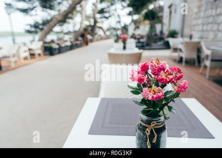 On the table in summer cafe stands bouquet of fresh flowers Stock Photo