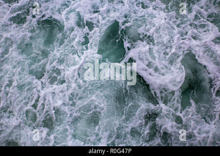 Waves breaking on the shore create white foamy churning water Stock Photo