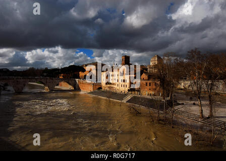 Winter in Rome. River is swollen along Tiber Island embankments under stormy clouds Stock Photo