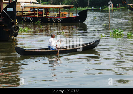Old man rows a traditional small boat on Alappuzha back waters, Kerala Stock Photo