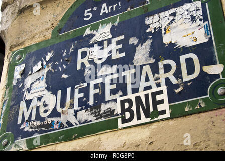 A traditional blue enamel street sign for Rue Mouffetard, a popular street of cafes, bars and shops, covered with stickers, Paris, France. Stock Photo