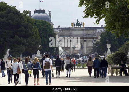 People walk through the Jardin des Tuileries toward the Arc de triomphe du Carrousel and the Louvre, Paris, France. Stock Photo