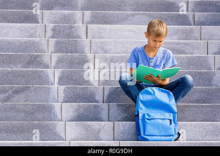 Boy sitting on the stairs and doing school homework Stock Photo