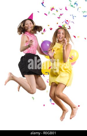 Party of teenage girls, girls with balloons, confetti in festive hats having fun, children are jumping, white background is isolated. Stock Photo