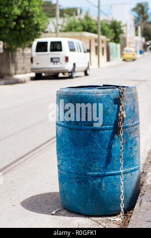 Plastic barrel with a chain used for waste collection on the street of Mexico Stock Photo