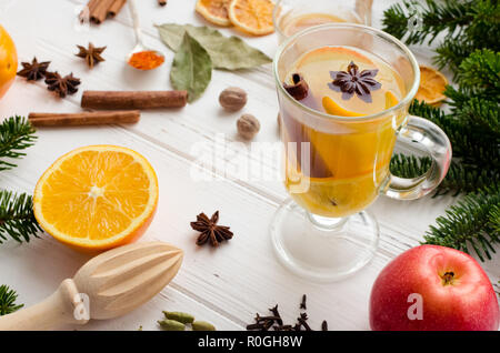 Christmas hot white mulled wine in glass with orange, honey, cinnamon sticks and star anise with spices and ingredients on white wooden background. Sp Stock Photo