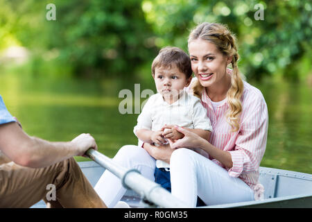 parents riding boat on lake with son at park Stock Photo