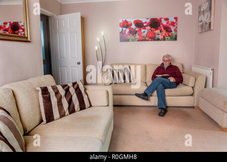 Senior man sitting alone, reading. Home alone loneliness single male. Stock Photo