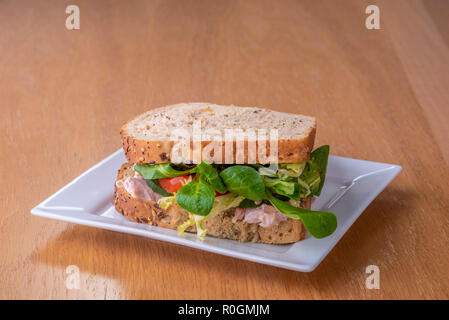 Chicken salad sandwich on a white plate.Turkey lettuce tomato granary bread. Stock Photo