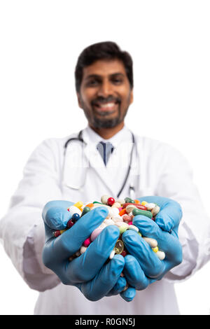 Indian male doctor handful of pills in palm isolated on white studio background Stock Photo