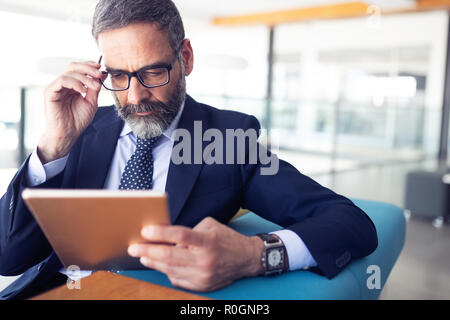 Serious man managing director of big prosperous company is holding touch pad Stock Photo