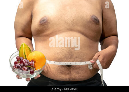 Man holding fruit in bowl and measuring his stomach with measuring tape isolated over white background. Fat man diet Stock Photo