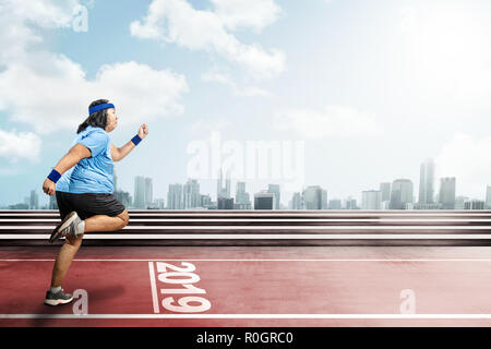 Asian fat man running on running track with 2019 number on the start line. New Year Resolution 2019 Stock Photo