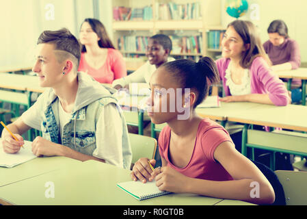 Positive multiethnic students studying together in the classroom Stock Photo