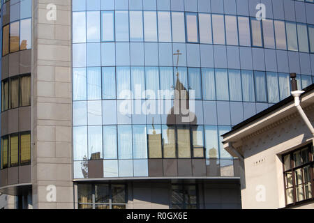 Distorted reflection of old orthodox cathedral in the windows of modern city building Stock Photo