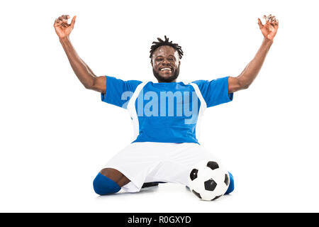 Football player with arms raised holding ball on black background