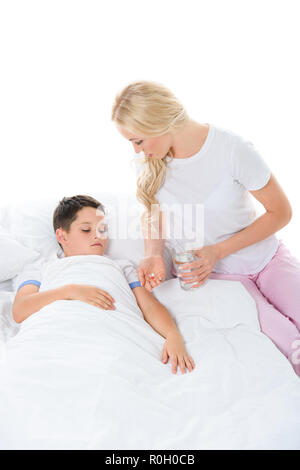 mother giving pills and glass of water to ill son, isolated on white Stock Photo