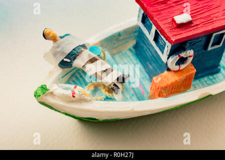 Tiny wrapped figurine of man model on a model boat Stock Photo