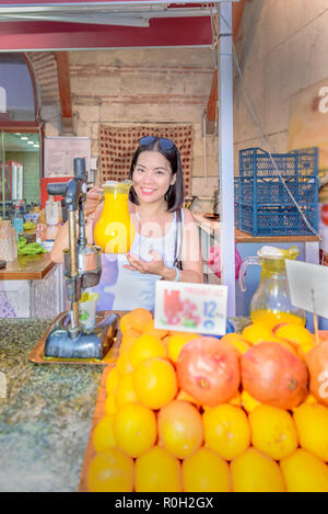 Beautiful woman holds orange juice jar behind fruit juice stall in Istanbul,Turkey Stock Photo