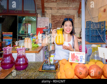 Beautiful woman holds orange juice jar behind fruit juice stall in Istanbul,Turkey Stock Photo