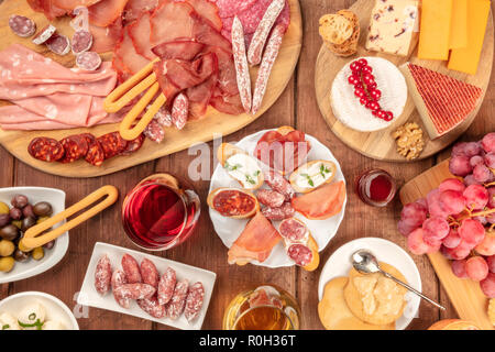 Charcuterie Tasting. A photo of many different sausages and hams, deli meats, and a cheese platter, shot from above on a rustic background with red wine Stock Photo