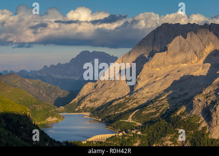 Sunset sunlight on Lake Fedaia and the Marmolada mountain group. In background Monte Civetta. The Dolomites. Italian Alps. Europe. Stock Photo