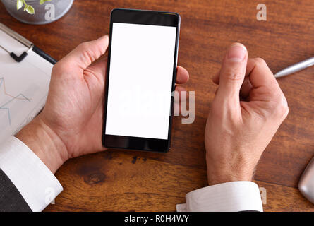 Businessman looking at a smartphone on brown wood table in the office. Horizontal composition. Top view Stock Photo