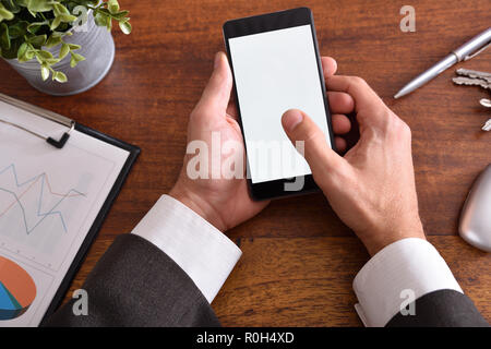 Businessman touching a smartphone on brown wood table in the office. Horizontal composition. Top view Stock Photo
