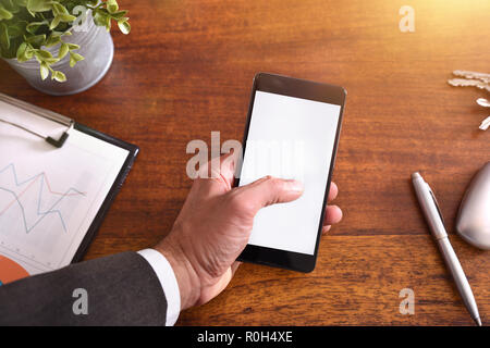Businessman touching a smartphone on brown wood table in the office. Horizontal composition. Top view Stock Photo