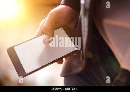 Businessman with gray jacket and blue jeans using a mobile phone in a room illuminated by the sun. Horizontal composition. Elevated view Stock Photo