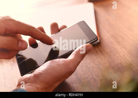 Hands of a man touching a telephone on a brown wooden table. Horizontal composition Stock Photo