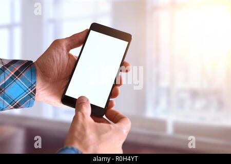 Hands of a man in blue plaid shirt using mobile phone at home in front of a window. Horizontal composition. Stock Photo
