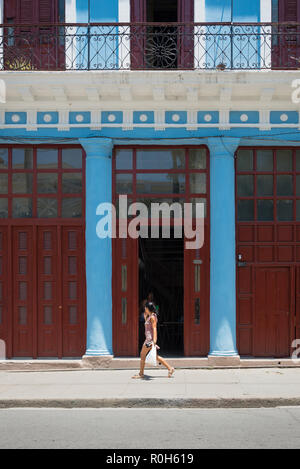 Woman walking past facade of old house in Cienfuegos, Cuba Stock Photo