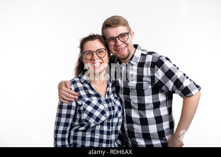 Nerds, geek, bespectacled and funny people concept - funny couple in glasses are hugging on white background Stock Photo