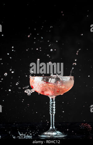 glass of red coctail with red fruits on black background, visible splashes, drops and movement of the liquid Stock Photo