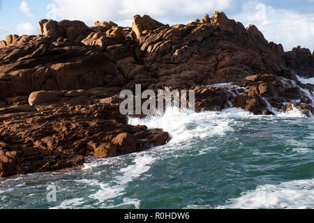 Rising tide and big waves hit rocky coast in sunlight in northern France. Stock Photo